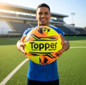 Bola Society Topper Nova Boleiro amarelo e laranja em campo de grama sintética.