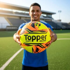 Bola Society Topper Nova Boleiro amarelo e laranja em campo de grama sintética.
